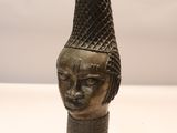 bronze head of a woman with a hat on her head
