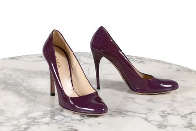 des talons hauts violets posés sur une table en marbre, sur fond blanc