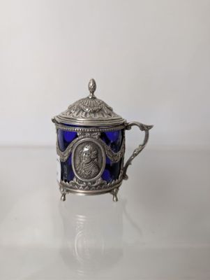 an antique silver and blue glass teapot on a white surface