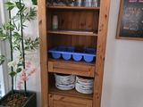 a tall wooden cabinet with dishes and glasses on it