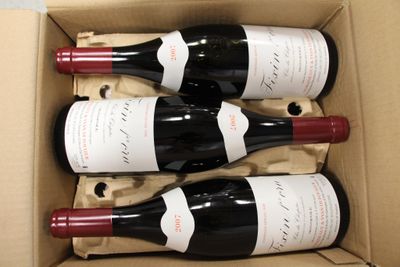 three bottles of red wine in a cardboard box on a table
