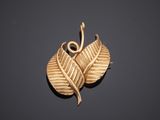 a close up of a gold leaf pendant on a black surface