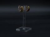 a close up of a pair of gold hoop earrings on a clear stand
