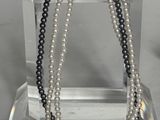 deux rangées de perles noires et blanches présentées sur un présentoir transparent