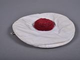 a red flower on a white cloth on a gray surface