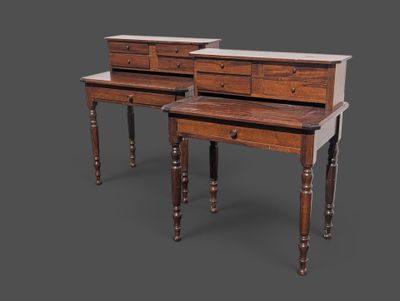 deux tables en bois surmontées de tiroirs, sur fond gris