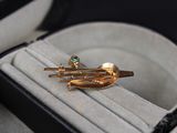 a ring in a box with a gold brooch on it