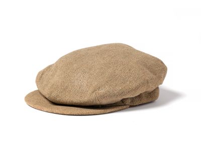 le chapeau est de couleur beige et est surmonté d'une calotte plate