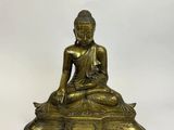 a brass statue of a buddha sitting on a rock