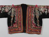 une veste noire et rouge brodée, avec des perles sur les épaules