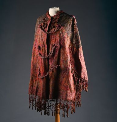 un châle rouge et noir à franges posé sur un support de mannequin
