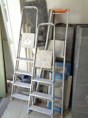 Plusieurs échelles sont empilées les unes sur les autres dans une pièce.