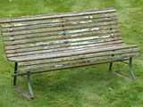 a wooden bench sitting in the middle of a grassy field