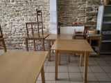 tables and chairs in a room with a stone wall behind them