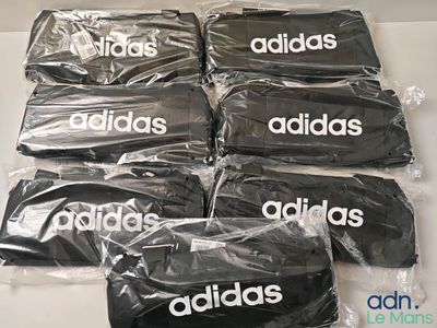 Six sacs Adidas sont emballés dans du plastique sur une table