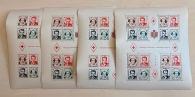 quatre timbres différents représentant des personnes, posés sur une feuille de papier posée sur une table