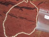 un collier de perles blanches et un sac en plastique posés sur une table