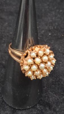 pearl and gold ring on a black cone on a black surface