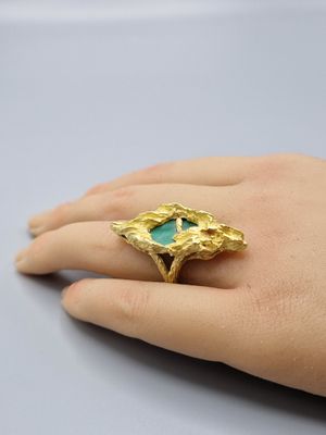 une image représentant la main d'une femme portant une bague en or sertie d'une pierre turquoise