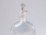 une bouteille en verre transparent avec un bouchon argenté, posée sur une table