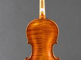 an antique violin on a stand with a gray background