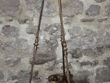 a large metal bell hanging from a chain on a stone wall