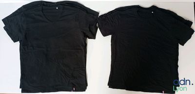 two black t - shirts sitting next to each other on a table