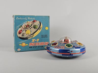 an old tin toy of a flying saucer with a box in the background