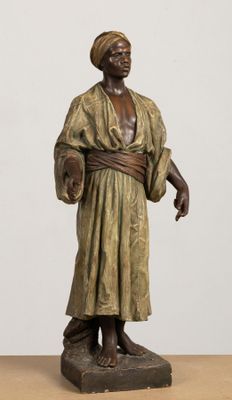 bronze statue of a man with a hat and robe on a wooden table