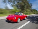 a red car driving down the road with trees in the background