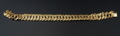 gros plan d'un bracelet en or sur une surface noire