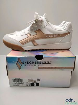 des baskets Skechers blanches et dorées posées sur une boîte