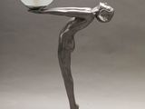 sculpture représentant une femme tenant une boule de verre posée sur une table