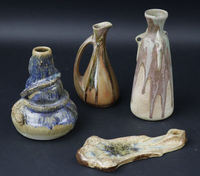 trois vases et un morceau de bois sont posés sur une surface noire