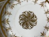 a white and gold plate with a gold flower on it