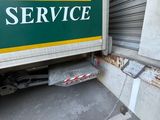 a green and yellow service truck parked next to a building