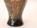 a vase that has a purple flower on it