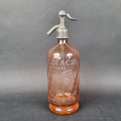 a pink glass bottle with a metal handle on a gray surface