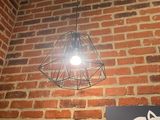 une lampe suspendue au plafond au-dessus d'une enseigne fixée sur un mur de briques
