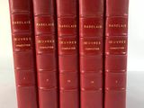 six livres rouges sont alignés sur une surface blanche