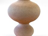 un petit vase posé sur une surface blanche