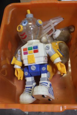 un robot jouet dans une boîte en plastique contenant un ours en peluche