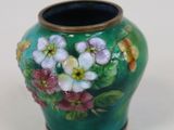 un vase avec des fleurs peintes dessus, posé sur une table