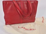 a red bag with a red handle sitting on top of a white bag