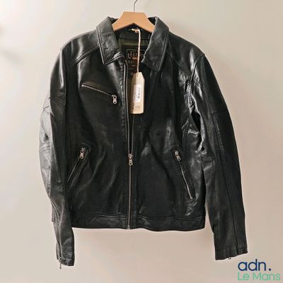 black leather jacket hanging on a hanger on a wall