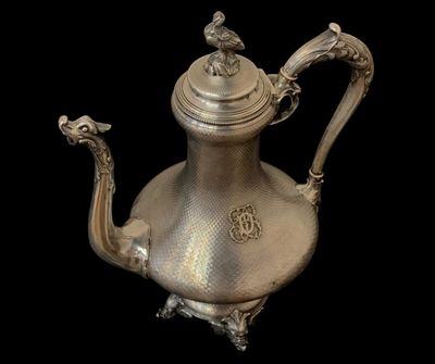 une théière ancienne en argent ornée d'un oiseau sur l'anse