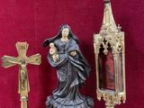 a statue of a woman holding a baby next to a cross and a mirror