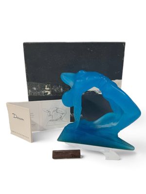 une photo d'une sculpture bleue posée à côté d'une boîte et d'un morceau de chocolat