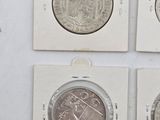 four different types of silver coins are displayed on a white surface