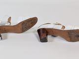 a pair of white leather shoes with wooden heel and heel strap